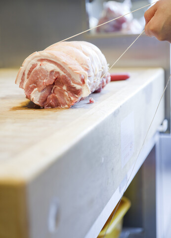 Close up of butchers hands tying meat joint in butchers shop stock photo