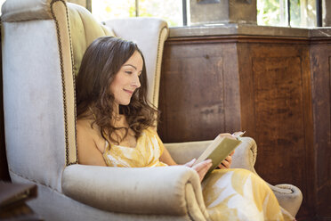 Frau liest ein Buch in einem alten Sessel in Thornbury Castle, South Gloucestershire, UK - CUF24707