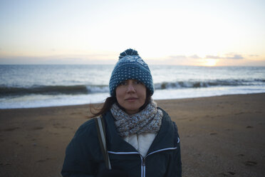 Porträt einer reifen Frau mit gestrickter Mütze am Strand in der Abenddämmerung - CUF24744