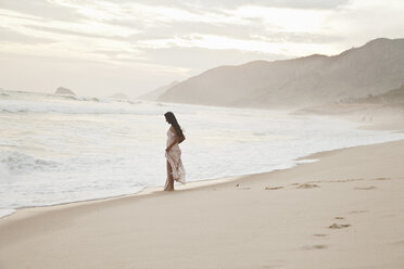 Mid adult woman walking along beach - CUF24762