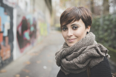 Junge Frau auf der Straße, Graffiti-Wand im Hintergrund - CUF24826