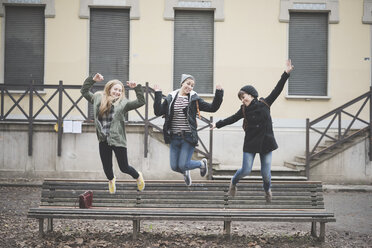Drei Schwestern springen auf einer Parkbank - CUF24846