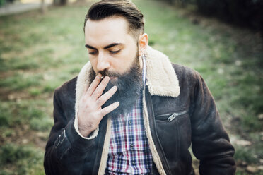 Young bearded man smoking in park - CUF24858