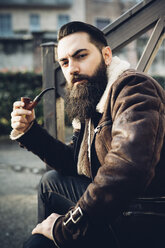 Young bearded man smoking pipe on steps - CUF24861