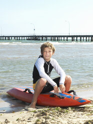 Porträt eines kleinen Jungen (Kindersurf-Rettungsschwimmer) auf einem Surfbrett sitzend, Altona, Melbourne, Australien - CUF24862