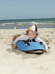 Porträt eines niedlichen kleinen Jungen (Kindersurf-Rettungsschwimmer) auf einem Surfbrett am Strand, Altona, Melbourne, Australien - CUF24865