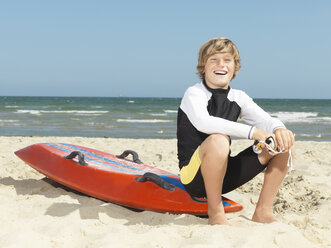 Porträt eines selbstbewussten kleinen Jungen (Kindersurf-Rettungsschwimmer) auf einem Surfbrett sitzend, Altona, Melbourne, Australien - CUF24866