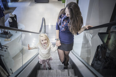 Mutter und kleine Tochter auf der Rolltreppe eines Einkaufszentrums - CUF24952