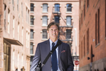 Businessman walking outdoors, smiling - ISF09338