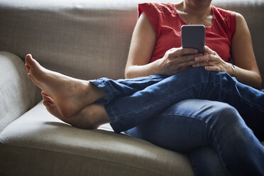 Beschnittene Ansicht von Mutter und Sohn, die sich auf dem Sofa entspannen und ihr Smartphone benutzen - ISF09362