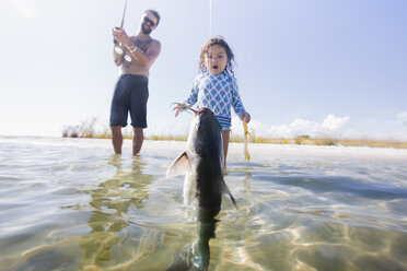 Daughter watching father catch fish in sea, Fort Walton Beach, Florida, USA - ISF09367