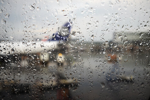 Window view of airplane parked in airport apron in rain - ISF09374