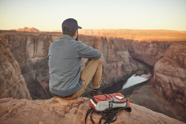 Mann sitzt auf einem Felsen und schaut auf die Aussicht, Rückansicht, Page, Arizona, USA - ISF09379