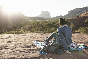 Frau sitzt auf einer Decke in der Wüste und schaut auf die Aussicht, Rückansicht, Sedona, Arizona, USA - ISF09390