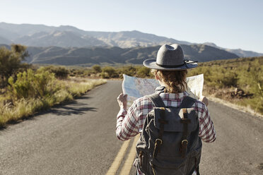 Frau steht auf einer Wüstenstraße und betrachtet eine Landkarte, Sedona, Arizona, USA - ISF09394