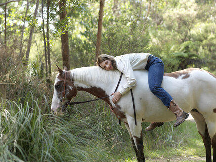 Porträt eines Teenagers, der ein Pferd umarmt, während er ohne Sattel reitet - CUF25049
