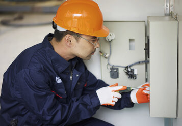 Arbeiter bei der Arbeit an einem Sicherungskasten in einer Kranfabrik, China - CUF25234