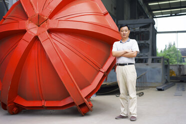 Arbeiter steht neben einem Teil in einer Kranfabrik, China - CUF25237