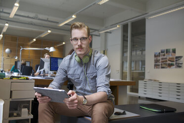 Porträt eines jungen Mannes, der ein digitales Tablet im Büro benutzt - CUF25345