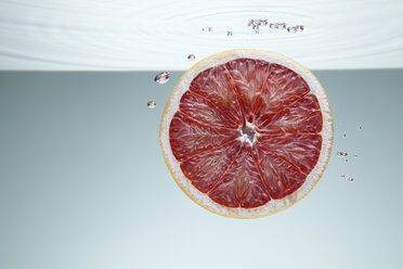 Slice of pink grapefruit underwater - CUF25574