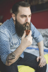 Young bearded man smoking pipe on bed - CUF25616