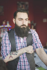 Young bearded man folding shirt sleeve - CUF25618