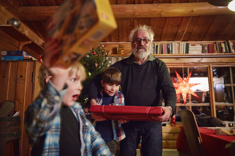 Joyful boy holding up Christmas present stock photo