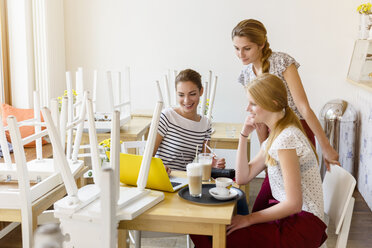 Three women using laptop in cafe - CUF25644