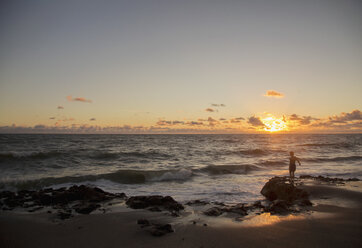 Junge schaut bei Sonnenaufgang aufs Meer hinaus, Blowing Rocks Preserve, Jupiter Island, Florida, USA - ISF09426