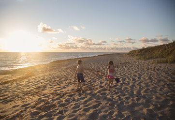 Boy and sister walking along beach at sunrise, Blowing Rocks Preserve, Jupiter Island, Florida, USA - ISF09427