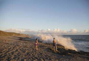 Junge und Schwester beobachten plätschernde Wellen vom Strand aus, Blowing Rocks Preserve, Jupiter Island, Florida, USA - ISF09428