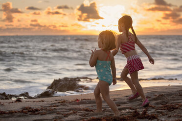 Mädchen und Schwester laufen bei Sonnenaufgang am Strand, Blowing Rocks Preserve, Jupiter Island, Florida, USA - ISF09436