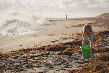 Mädchen spielt mit Spielzeugeimer am windigen Strand, Blowing Rocks Preserve, Jupiter Island, Florida, USA - ISF09439