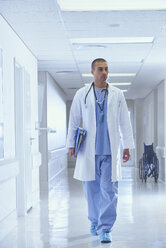 Ein Arzt geht mit medizinischen Notizen einen Krankenhausflur entlang - CUF25786