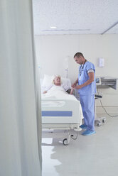 Krankenpfleger mit Blutdruckmessgerät an älterer Patientin im Krankenhausbett - CUF25805