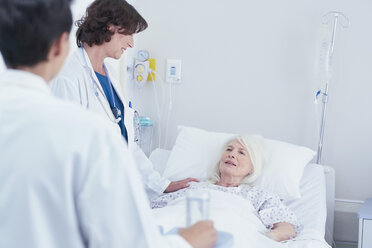 Ärzte erklären einer älteren Patientin im Krankenhausbett - CUF25808