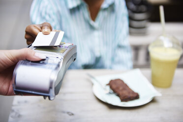 Woman paying by credit card at pavement cafe, close-up - ABIF00564