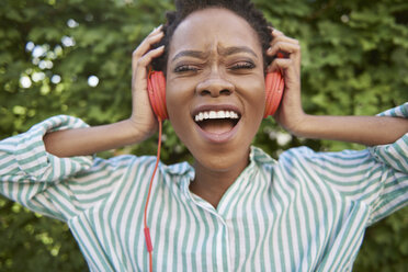 Portrait of singing young woman with headphones - ABIF00581