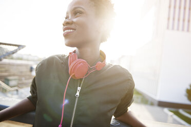 Smiling young woman with headphones at backlight - ABIF00585