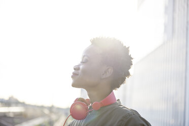 Profile of young woman with red headphones at backlight - ABIF00587