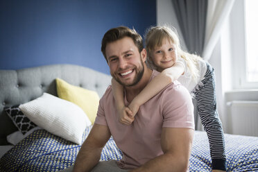 Glücklicher Vater und Tochter auf dem Bett sitzend, sich umarmend - AWF00001