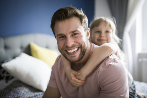 Glücklicher Vater und Tochter auf dem Bett sitzend, sich umarmend - AWF00002