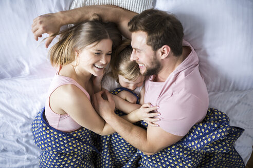 Glückliche Familie im Bett liegend, kuschelnd - AWF00003