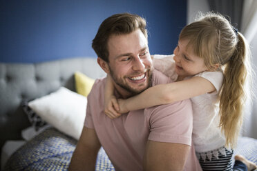 Happy father and daughter sitting on bed, embracing - AWF00007