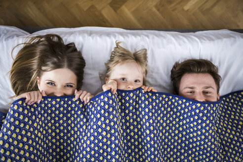Happy family lying in bed, hiding under blanket - AWF00010