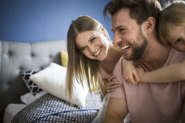 Happy family lsitting on bed, embracing - AWF00011