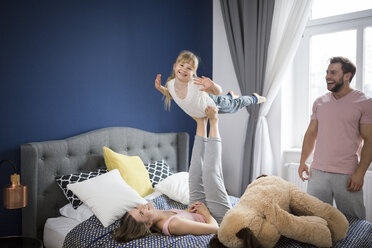 Familie spielt im Schlafzimmer, Mutter balanciert Tochter auf ihren Füßen - AWF00016