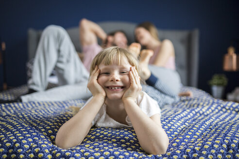 Freches kleines Mädchen auf dem Bett liegend mit ihren Eltern - AWF00030