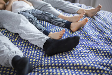 Family of three lying on bed, low section - AWF00033