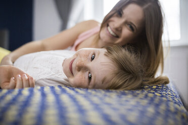 Happy mother and daughter lying on bed - AWF00037